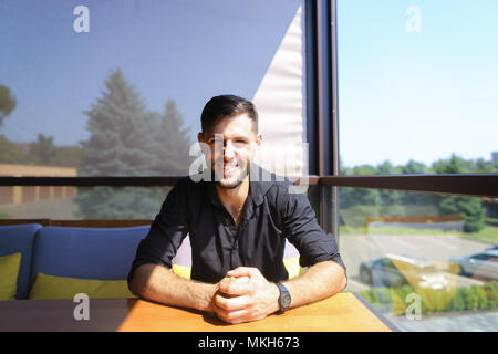 Young businessman sitting at office on sofa and wearing black shirt. Stock Photo