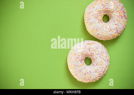 two glazed donut isolated on green background. Coffe break snack.Top view, copy space. tasty donuts. Stock Photo