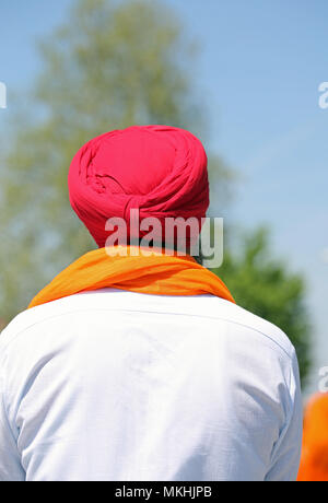 man with red turban white shirt and orange scarf from behind