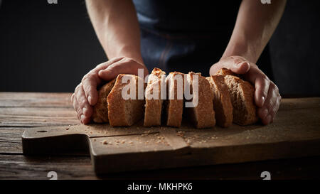 chef holding a bread in front of a wooden cutting board Stock Photo