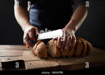 grain bread put on kitchen wood plate with a chef holding knife for cut Stock Photo