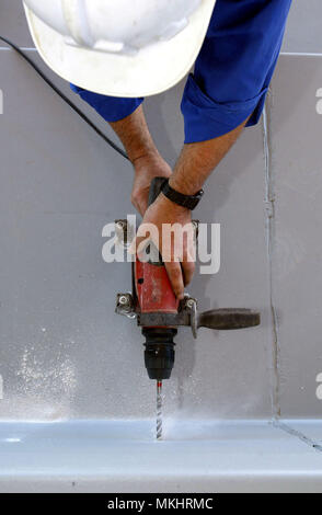 Overhead view of a man drilling a cement wall with a power drill Stock Photo