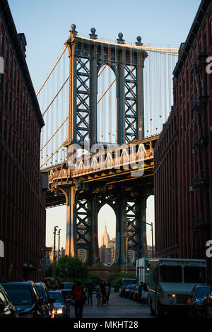 Brooklyn bridge seen from a narrow alley enclosed by two brick buildings during the sunset. New York City, USA. Stock Photo
