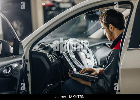 Professional car mechanic working in auto repair service with special laptop for automatic fix Stock Photo