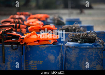 Fisherman rope on plastic barrels with orange life jackets in background Stock Photo