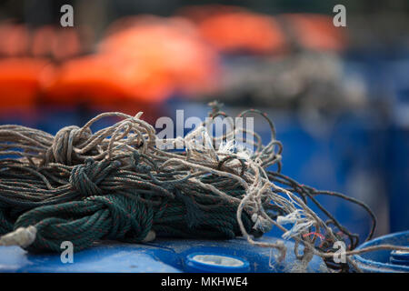 Fisherman rope on plastic barrels with orange life jackets in background Stock Photo