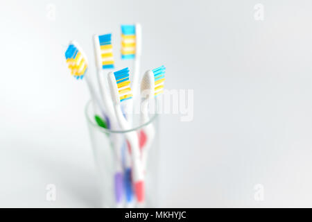 Group of plastic white toothbrushes in different colors in glass on white background. Free copy space. Stock Photo