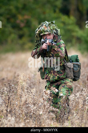 1970 – 1980 British Army soldier in camouflage suit and steel helmet carrying a SLR (Self-Loading Rifle) L1A1 - calibre of 7.62 mm (Posed by Model) Stock Photo