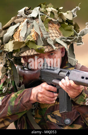 1970 – 1980 British Army soldier in camouflage suit and steel helmet carrying a SLR (Self-Loading Rifle) L1A1 - calibre of 7.62 mm (Posed by Model) Stock Photo