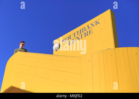 South Bank, London, 7th May 2018. The Southbank Centre logo and brutalist congrete stairs in yellow stand out against the bright blue sky. Tourists and Londoners enjoy the sunny weather on the South Bank of London by the river Thames, with record breaking temperatures of up to 28 degrees. Credit: Imageplotter News and Sports/Alamy Live News Stock Photo