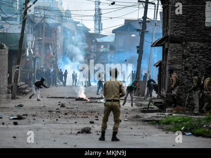 Srinagar, Kashmir. 8th May 2018. Kashmiri protesters throw stones towards policeman during clashes in Srinagar, Kashmir. Fierce clashes broke out between government forces and Kashmiri protesters in Srinagar on Tuesday as the valley continued to remain tense over the killing of 11 people including 5 militants and 6 civilians in Kashmir. Police used tear smoke shells and shot gun pellets to disperse hundreds of demonstrators who hurled rocks and chanted anti-and pro-freedom slogans. Credit: SOPA Images Limited/Alamy Live News Stock Photo
