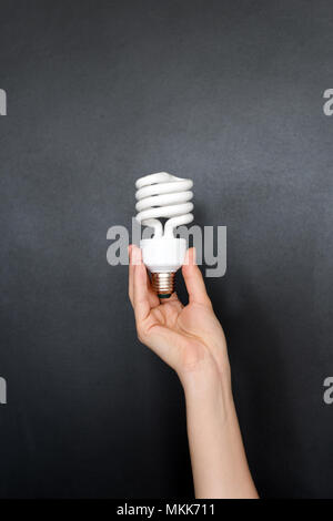 Recycling, electricity, environment and ecology concept - close up of hand holding energy saving lightbulb or lamp. Compact fluorescent light bulb on  Stock Photo
