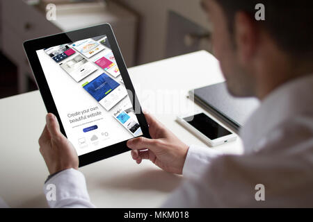 bussinessman at office holding a tablet showing builder website. All screen graphics are made up. Stock Photo
