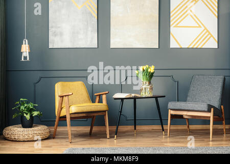 Retro chairs in vintage living room interior with paintings, lamp, plant and book on the table Stock Photo