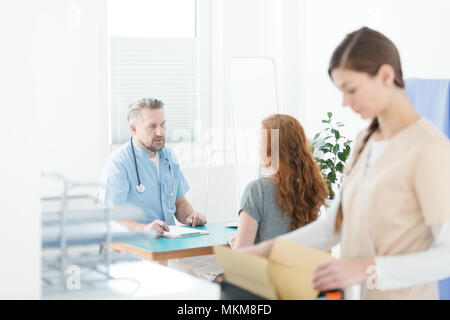 General practitioner in blue uniform with stethoscope during medical consultation with a patient Stock Photo