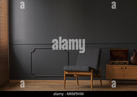 Grey armchair on the grey empty wall with molding in living room interior with wooden floor Stock Photo