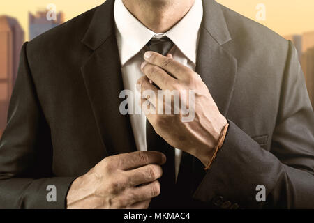 man dressed in suit and white shirt adjusts his tie Stock Photo