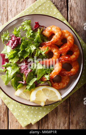 Honey soy king prawns and fresh salad close-up on a plate on a table. Vertical top view from above Stock Photo