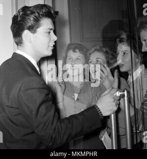 To celebrate his millionth record of 'Living Doll' Cliff Richard went to the EMI factory at Hayes, Middlesex. After being presented with a gold pencil by Mr J E Lockwood, Chairman of EMI, Cliff was mobbed and kissed by factory girls. Pictured, the girls are behind a locked glass door. 5th November 1959. Stock Photo