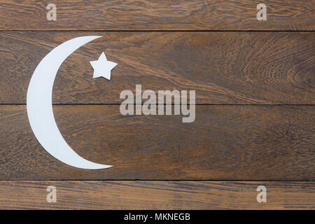 Table top view aerial image of decorations Ramadan Kareem holiday background.Flat lay DIY paper cut of white moon and star on modern rustic brown wood Stock Photo