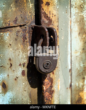 Close up of rusty padlock on old painted metal door Stock Photo