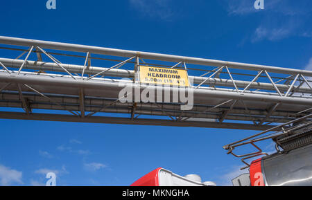 Headroom warning sign on an industrial plant for traffic allowing up to 5.60m (18'4') with passing HGV tanker underneath. Stock Photo