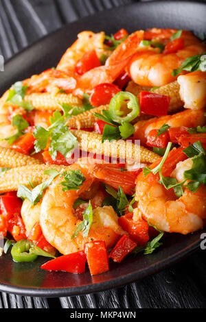 Fried prawns with pepper, garlic, corn cob and herbs close-up on a plate. vertical Stock Photo