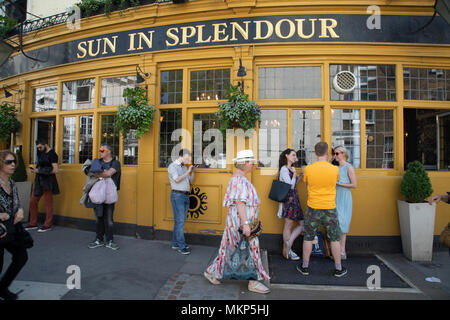 The Sun in Splendour pub on the corner of Portobello Road Market in Notting Hill, West London, England, United Kingdom. People enjoying a sunny day out hanging out at the famous Sunday market, when the antique stalls line the street.  Portobello Market is the worlds largest antiques market with over 1,000 dealers selling every kind of antique and collectible. Visitors flock from all over the world to walk along one of Londons best loved streets. Stock Photo