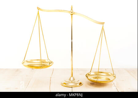 Golden brass balance scale on wooden desk background. Weight balance or imbalance, Symbol of law justice, libra, decision. Stock Photo