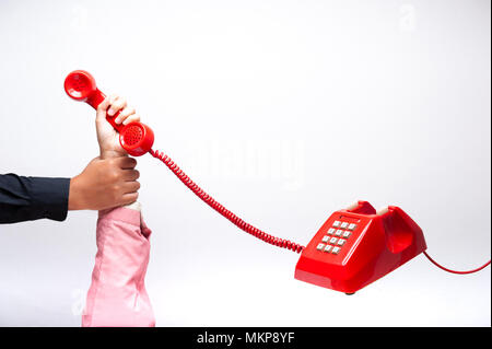Pull up someone's hand while using the telephone, hand holding telephone, classic red telephone receiver, old telephone on white background flying in  Stock Photo