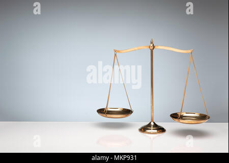Gold brass balance scale, weight balance scale on white desktop with gray background. Stock Photo