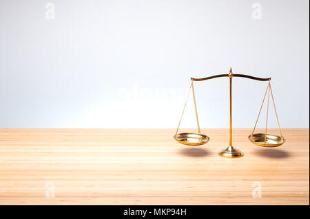 Gold brass balance scale, weight balance scale on wooden desktop with gray background. Top view. Stock Photo