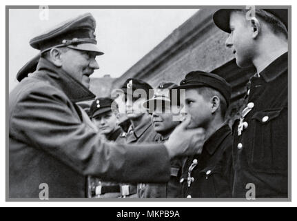 ADOLF HITLER 1945 Vintage German WW2 Propaganda Image. Nazi leader Adolf Hitler making probably his last public appearance outside his Berlin Bunker, meeting and awarding medals to loyal Hitler Youth members. Boys used as cannon fodder against overpowering Russian encirclement April 1945 WW2 Stock Photo