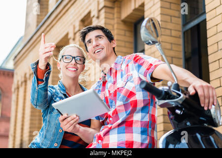 Couple on city trip planning their Vespa tour using tablet PC Stock Photo