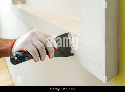 Decorative plaster coating. Man does ragged texture on the wall using a spatula. Stock Photo