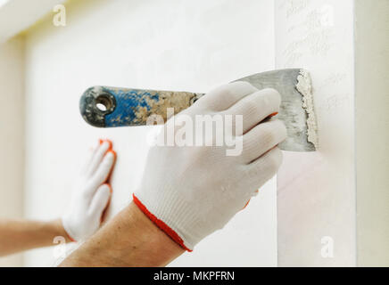 Decorative plaster coating. Man does ragged texture on the wall using a spatula. Stock Photo