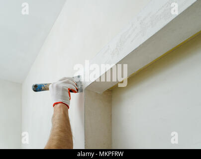 Decorative plaster coating. Man does ragged texture on the wall using a spatula. Stock Photo