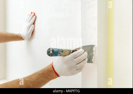 Decorative plaster coating. Man does ragged texture on the wall using a spatula. Stock Photo