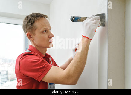 Decorative plaster coating. Man does ragged texture on the wall using a spatula. Stock Photo