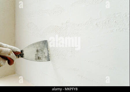 Decorative plaster coating. Man does ragged texture on the wall using a spatula. Stock Photo