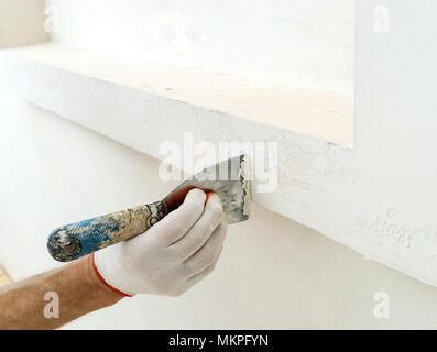 Decorative plaster coating. Man does ragged texture on the wall using a spatula. Stock Photo