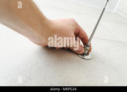 Worker uses a screwdriver to install the bracket for towel warmer. Stock Photo