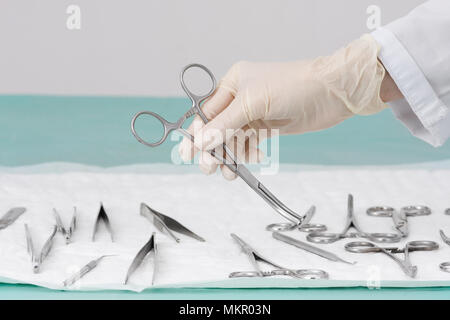 hand of doctor in medical glove holding medical arterial clamp Stock Photo