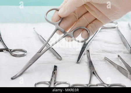 hand of doctor in medical glove with medical arterial clamp Stock Photo