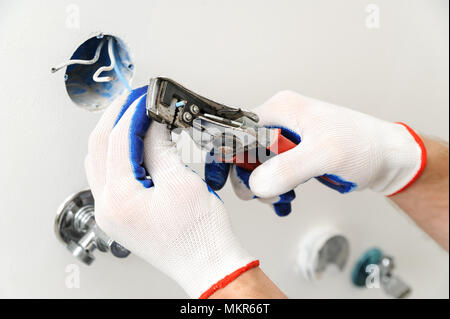 Electrician stripping insulation from wire for installing an electrical outlet. Stock Photo