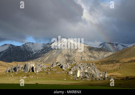 A faint rainbow hangs over the limestone outcrops at Castle Hill, South Island, New Zealand Stock Photo