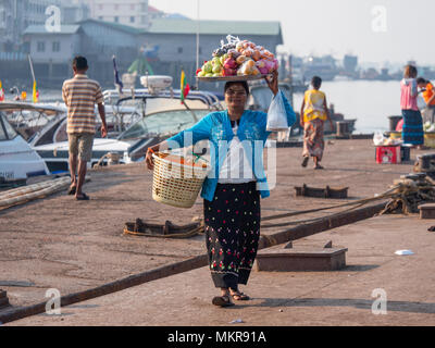 Woman carrying fruit to sell to passengers leaving on local ferries from Myeik, formerly Mergui, the largest city in the Tanintharyi Region of Myanmar Stock Photo