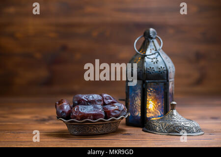 vintage Arabic lamp with plate of dates on wooden background, concept Ramadan Kareem Stock Photo