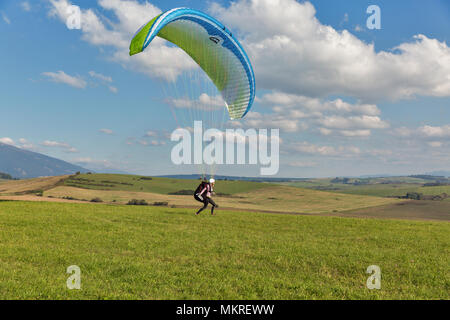 LIPTOVSKY TRNOVEC, SLOVAKIA - SEPTEMBER 30, 2017: Young woman paraglider starts flight from the hill close to Tatras mountains. Extreme sports activit Stock Photo
