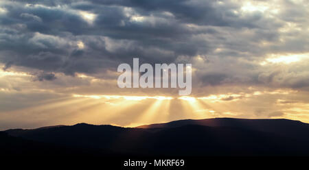Beautiful sunset landscape with sunrays on a cloudy sky Stock Photo